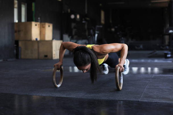 Sporty indian strong woman doing push-ups on rings - Photo, image