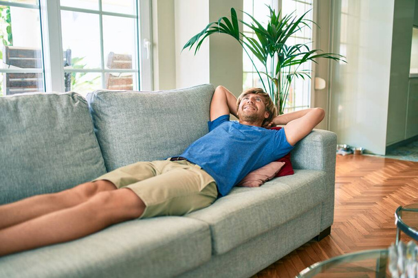 Μεσήλικας όμορφος καυκάσιος άντρας χαλαρώνει ξαπλωμένος άνετα στον καναπέ στο σπίτι - Φωτογραφία, εικόνα