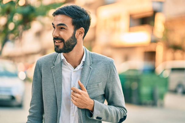 Mladý hispánský obchodník se šťastně usmívá, když stojí ve městě. - Fotografie, Obrázek