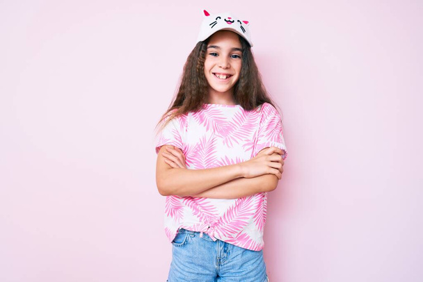 Cute hispanic child girl wearing casual clothes and funny kitty cap happy face smiling with crossed arms looking at the camera. positive person.  - Photo, Image
