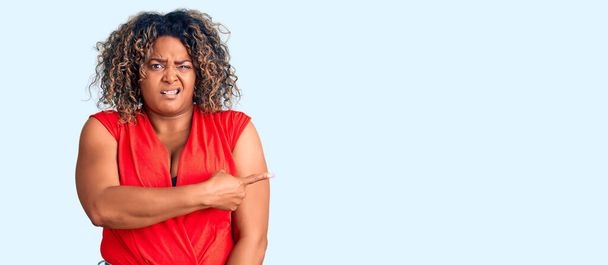 Молодой африканский американец плюс размер женщины носить случайный стиль с рубашкой без рукавов указывая в сторону обеспокоенный и нервный с указательным пальцем, обеспокоенный и удивленный выражение  - Фото, изображение