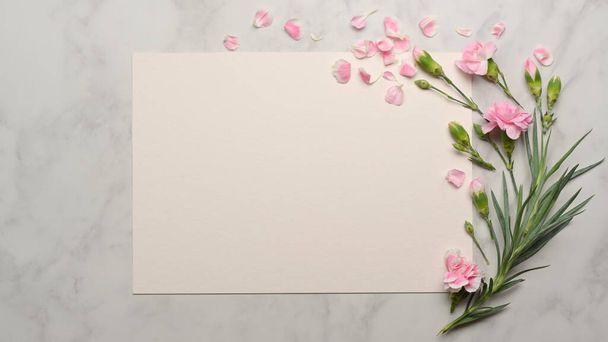 Widok góry makiety papieru i różowy kwiat urządzone na marmurowym biurku - Zdjęcie, obraz