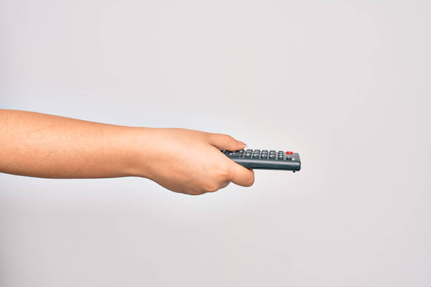 İzole edilmiş beyaz arka plan üzerinde uzaktan kumandalı televizyon kanalı değiştiren beyaz bir kadının eli - Fotoğraf, Görsel
