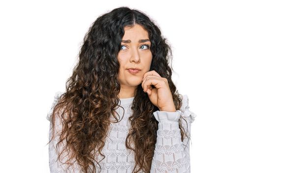 Fiatal spanyol lány viselése alkalmi ruhák komoly arc gondolkodás kérdés kézzel az állon, gondolkodó zavaros ötlet  - Fotó, kép