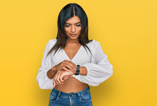 Молода латинська транссексуальна жінка в повсякденному одязі перевіряє час на наручних годинниках, спокійно і впевнено
  - Фото, зображення