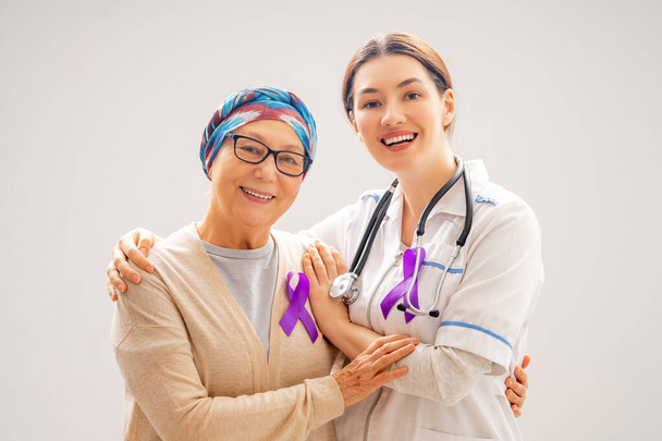February 4 World Cancer Day. Female patient and a doctor on grey wall background. Raising knowledge on people living with tumor illness. - Φωτογραφία, εικόνα