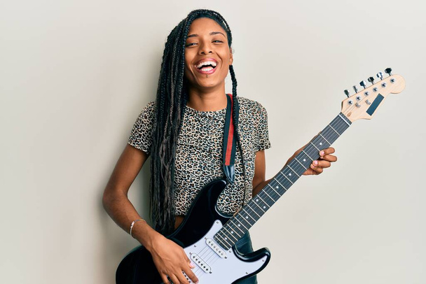 Africano americano mulher tocando guitarra elétrica sorrindo e rindo duro em voz alta, porque engraçado louco piada.  - Foto, Imagem