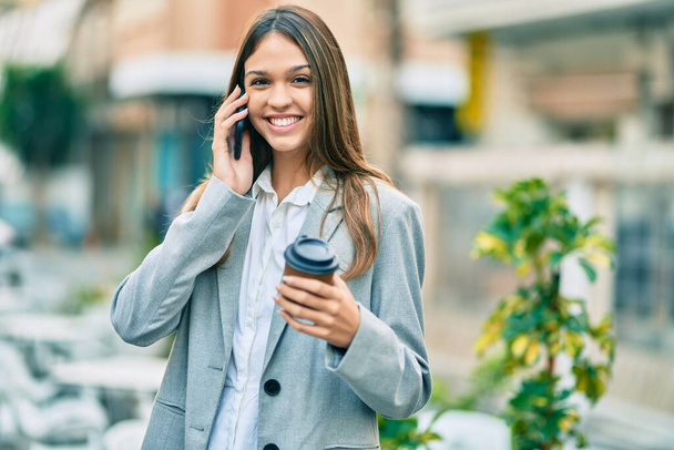 Jeune femme d'affaires latine parlant sur le smartphone boire du café à la ville. - Photo, image