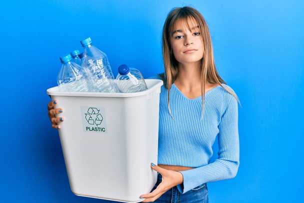 Teenager caucasian girl holding recycling bag with plastic bottles relaxed with serious expression on face. simple and natural looking at the camera.  - Fotó, kép