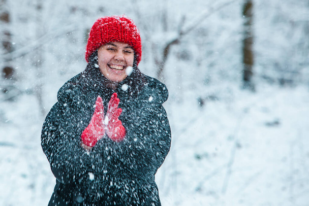 портрет молодой красивой женщины в зимнем наряде посреди снежного леса. - Фото, изображение