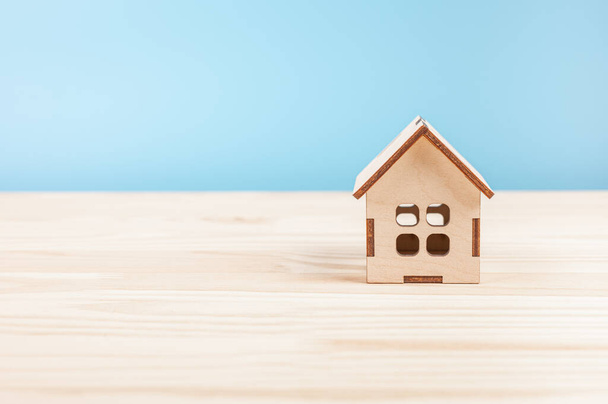 small wooden model house on wood table. Mini residential craft house on blue background. Small home model. Family life and business real estate, insurance, Mortgage concept. - Photo, image