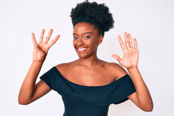 Młoda Afroamerykanka ubrana w luźne ubrania, pokazująca i wskazująca palcami numer dziewięć, uśmiechnięta pewna siebie i szczęśliwa..  - Zdjęcie, obraz