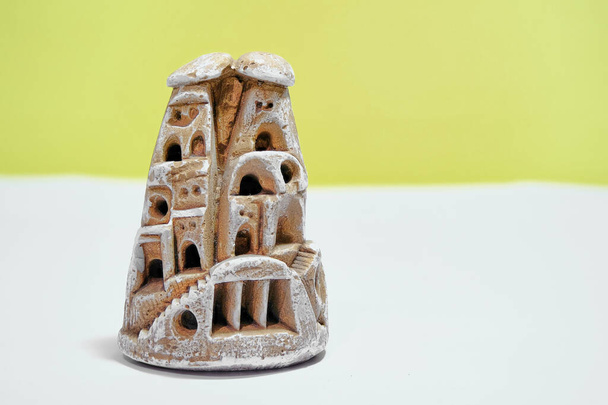 Miniature fairy chimney trinket made of gypsum block. Isolated yellow background and white ground.  - Photo, Image