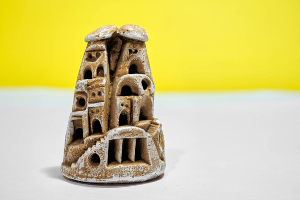 Miniaturowy wróżkowy komin wykonany z bloku gipsowego. Pojedyncze żółte tło i biała ziemia.  - Zdjęcie, obraz