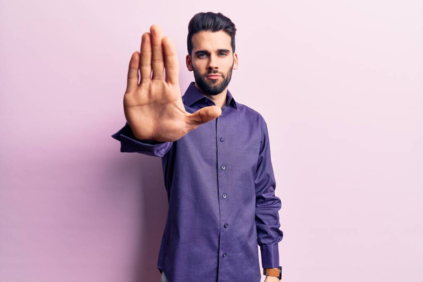 Young handsome man with beard wearing casual shirt doing stop sing with palm of the hand. warning expression with negative and serious gesture on the face.  - Photo, Image