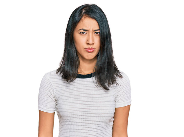 Bella asiatica giovane donna indossa casual t shirt bianca scettica e nervosa, accigliata sconvolta a causa di un problema. persona negativa.  - Foto, immagini
