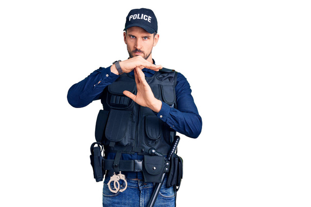 Young handsome man wearing police uniform doing time out gesture with hands, frustrated and serious face  - Photo, Image