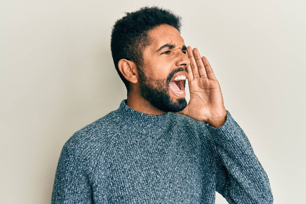 Handsome hispanic man with beard wearing casual clothes shouting and screaming loud to side with hand on mouth. communication concept.  - Fotó, kép