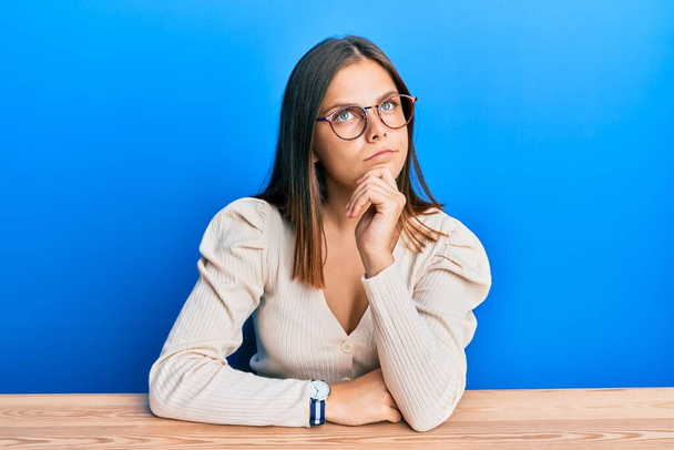 Young caucasian woman wearing casual clothes and glasses thinking concentrated about doubt with finger on chin and looking up wondering  - Photo, Image