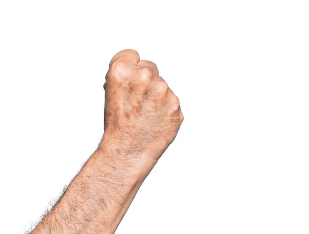 Hand eines kaukasischen Mannes mittleren Alters über isoliertem weißem Hintergrund, der Protest und Geste der Revolution macht, die Faust Kraft und Macht ausdrückt - Foto, Bild