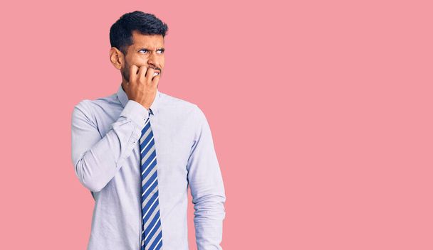 Young latin man wearing business clothes looking stressed and nervous with hands on mouth biting nails. anxiety problem.  - Photo, Image