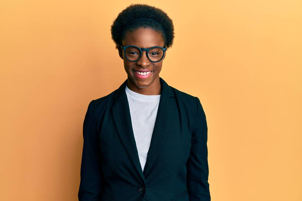 Jovem afro-americana vestindo jaqueta de negócios e óculos com um sorriso feliz e legal no rosto. pessoa de sorte.  - Foto, Imagem
