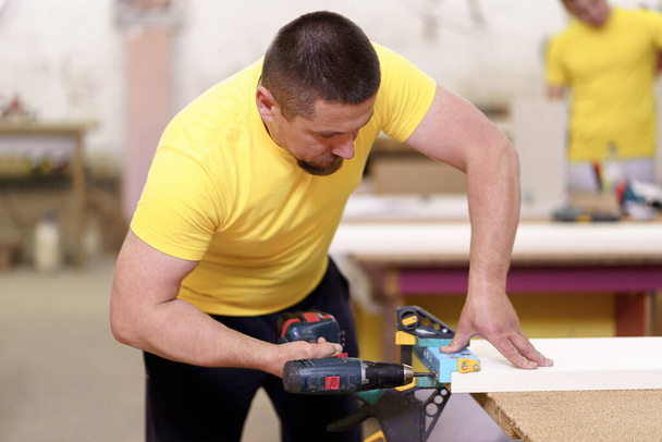O carpinteiro faz furos para montar móveis usando equipamentos - Foto, Imagem