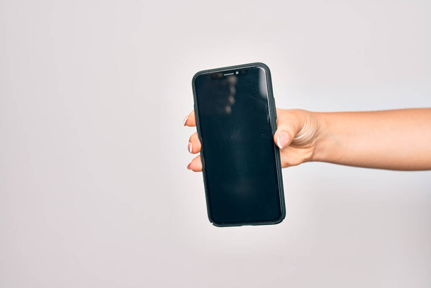 ręka kaukaska młoda kobieta trzyma smartfon pokazując ekran na odizolowanym białym tle - Zdjęcie, obraz
