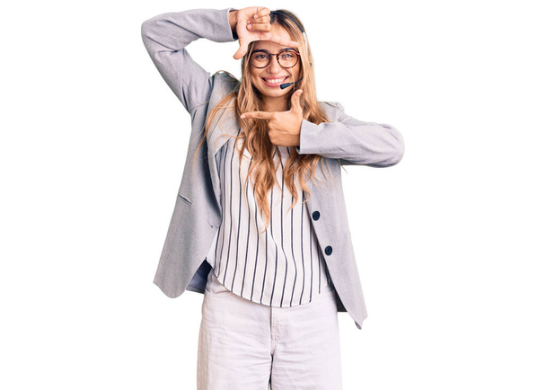 Fiatal gyönyörű szőke nő visel call center ügynök headset mosolygós így keret kezek és ujjak boldog arcát. kreativitás és fényképezés koncepció.  - Fotó, kép