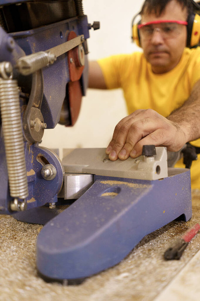 Плотник-мужчина с помощью пилы для резки дерева в мастерской - Фото, изображение