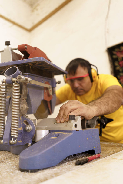 Carpintero macho que usa sierra para cortar madera en taller - Foto, Imagen