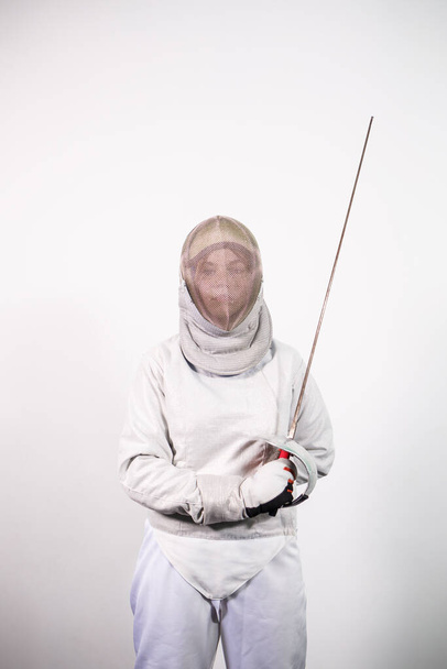 Girl in a fencing costume with a sword in hand isolated on white studio background. Young girls practice and exercise. Sports, healthy lifestyle. - Photo, Image