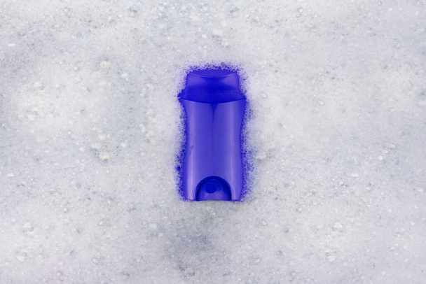 洗剤のボトルは泡に浮かんでいます。家庭用化学物質の危険性の概念。ナトリウム、受賞者パラベン、硫酸塩および泡中の他の有害化学物質。乾燥消臭スティック - 写真・画像