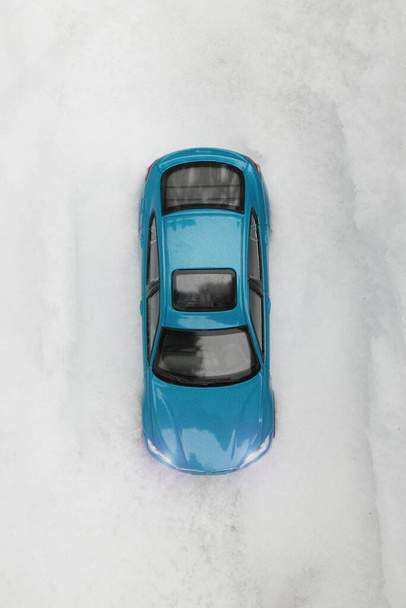 Vue aérienne de la voiture de tourisme bleue dans la neige profonde.Une voiture de tourisme bleue sans conducteur se tient sur la route dans la neige profonde. La route n'est pas visible à travers la neige. - Photo, image