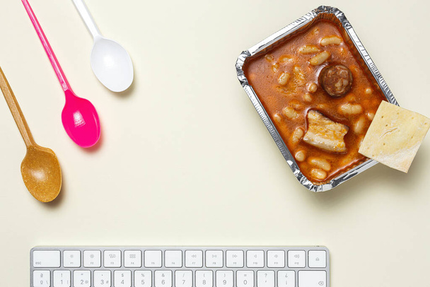 Lunch at work place Beans with chorizo and meat in aluminium container on work table, take away. Home food for office concept - Photo, Image