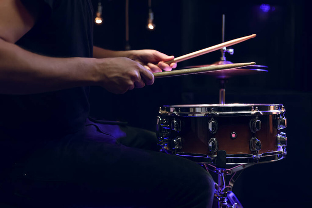 Baterista tocando palos de tambor en un tambor de caja en la oscuridad. Concepto de concierto y performance en vivo. - Foto, imagen