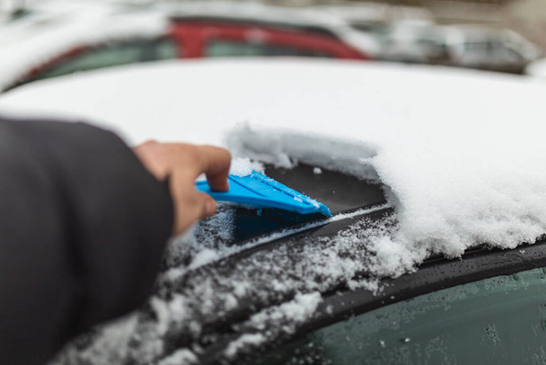 Transport, zima, pogoda, ludzie i koncepcja pojazdu - człowiek czyszczący śnieg z samochodu szczotką - Zdjęcie, obraz