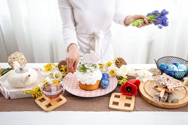 A woman decorates an Easter cake with flowers. Easter holiday concept. - Φωτογραφία, εικόνα