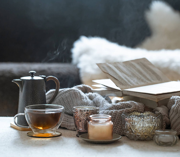 Νεκρή ζωή με ένα φλιτζάνι τσάι, μια τσαγιέρα, ένα βιβλίο και όμορφα vintage κηροπήγια με κεριά. Αρχική διακόσμηση έννοια. - Φωτογραφία, εικόνα