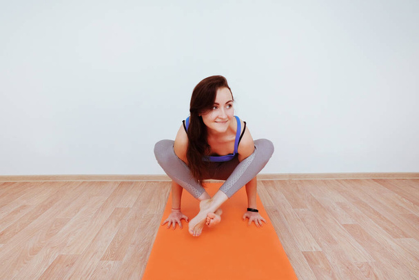 Donna che fa esercizio di yoga su tappeto arancione, stretching. - Foto, immagini