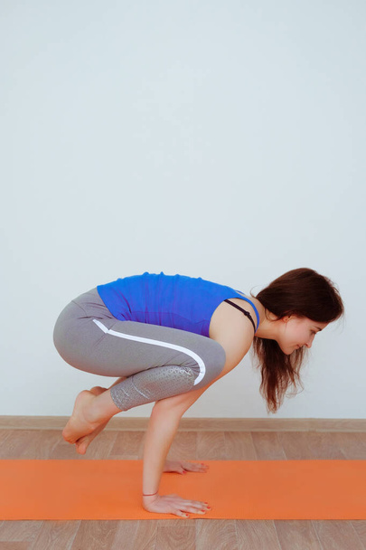 vrouw doet yoga oefening op oranje mat, stretching. - Foto, afbeelding