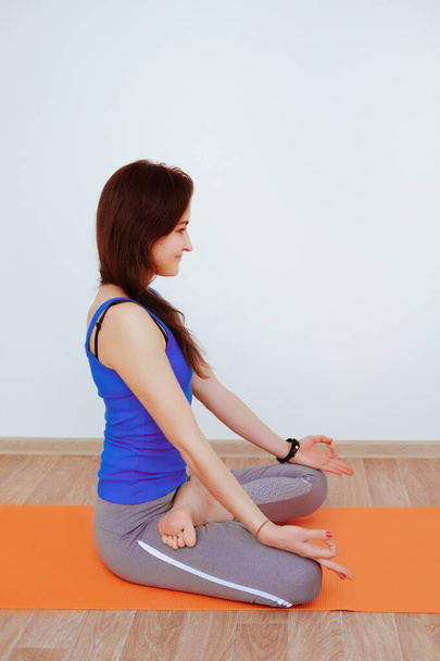 Mujer haciendo ejercicio de yoga sobre alfombra naranja, estiramiento. - Foto, imagen