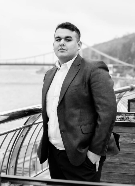 Young plus size man relaxing and enjoying the view city, plump people concept, one in big city life. Image of overweight businessman at downtown - Foto, afbeelding