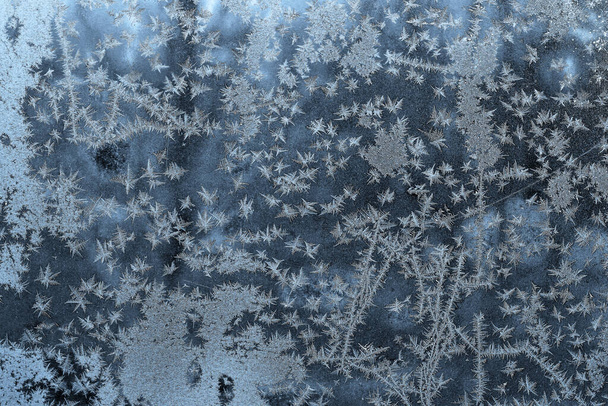 Mooie winterse achtergrond met bevroren glas en witte sneeuwvlokken - Foto, afbeelding