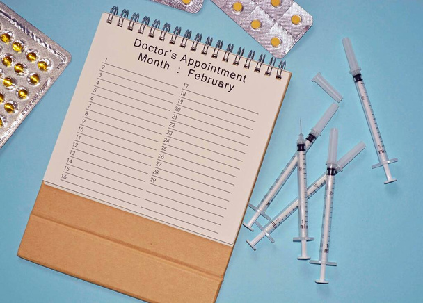 Календарь врачебных встреч с одноразовыми шприцами для инъекций и лекарствами - Фото, изображение
