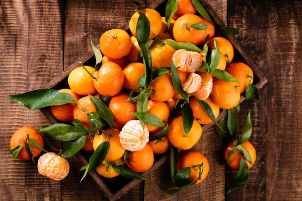 Fresh mandarin oranges fruit with leaves in wooden box, top view. - Fotografie, Obrázek