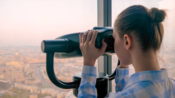 Fiatal nő néz keresztül turisztikai teleszkóp, felfedező látványos városkép - Fotó, kép
