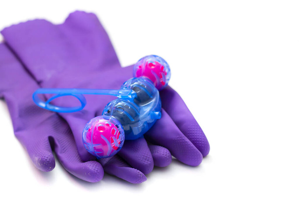Persona en guantes de goma protectora púrpura sostiene bolas multicolores de limpiador de inodoros. aislado en el aislamiento de fondo blanco. Enfoque selectivo, primer plano - Foto, imagen