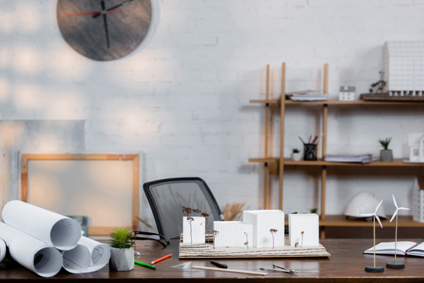 скрученные чертежи, архитектурные макеты и модели ветряных турбин на столе в офисе - Фото, изображение