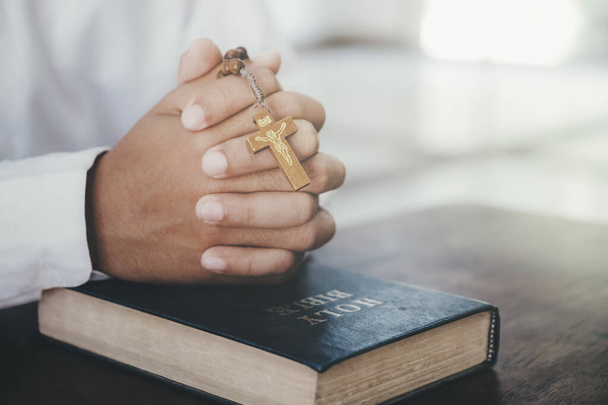 Religion, Christentum, Beten. Mann betet, die Hände an ihrer Bibel zusammengeklammert. - Foto, Bild